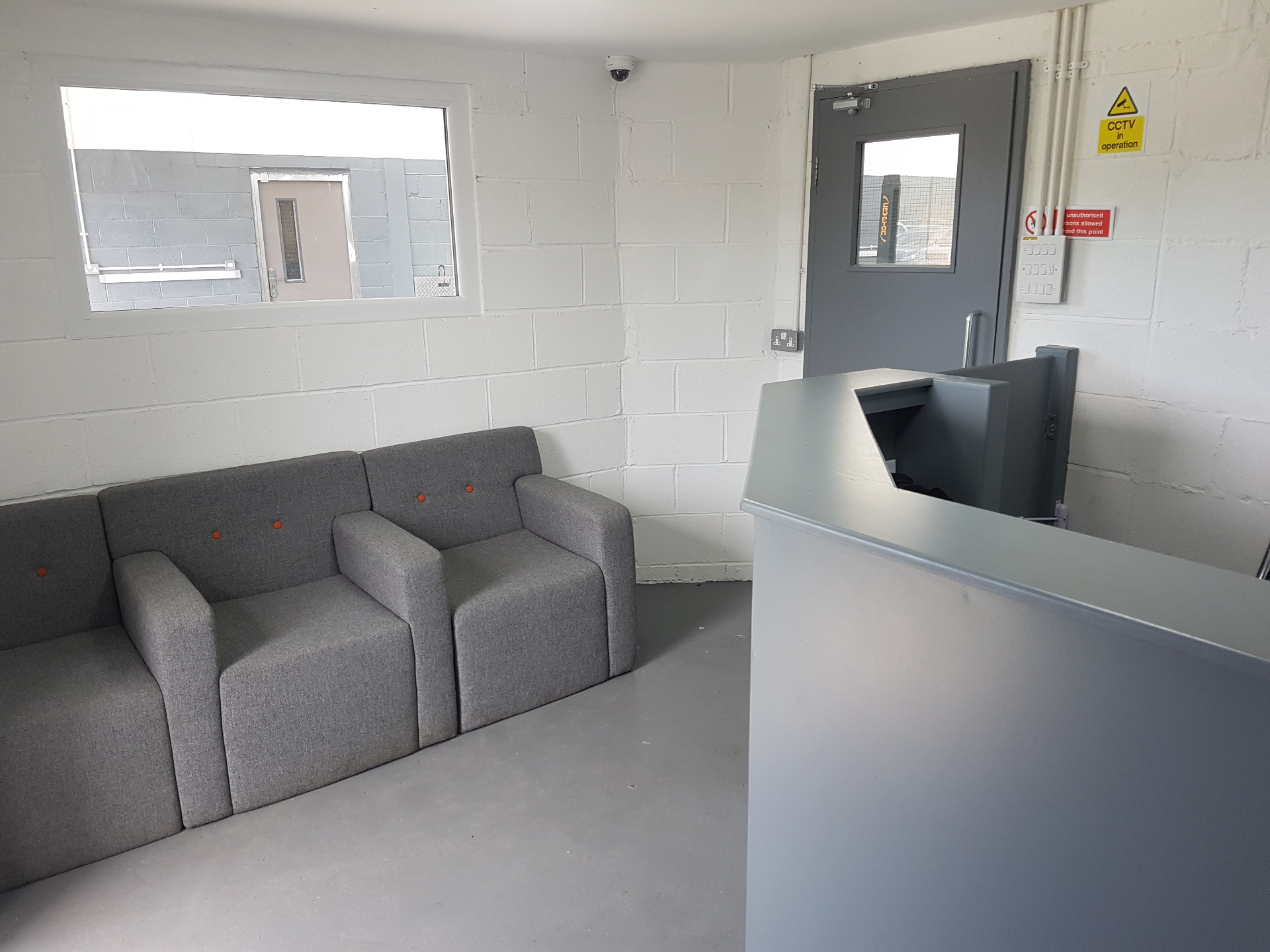 Customer waiting area with grey sofa and view into the workshop